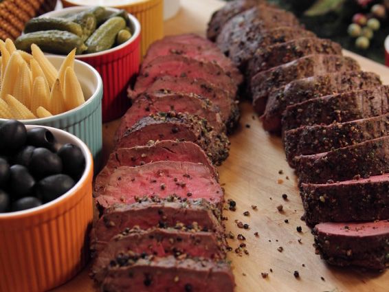 the meat is sliced up and ready to be served with olives, pickles, and jalapenos