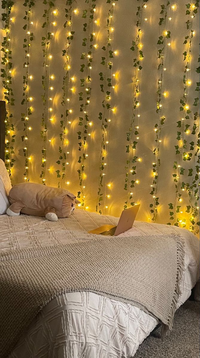 a bed with a laptop on top of it next to a wall covered in lights