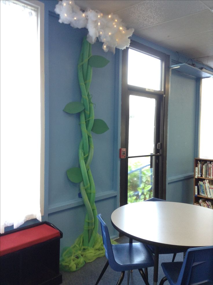 a room with a table, chairs and a book shelf in it that is decorated like a vine