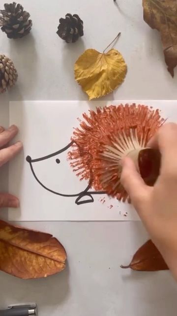 someone is drawing a hedge on paper with leaves and acorns next to it