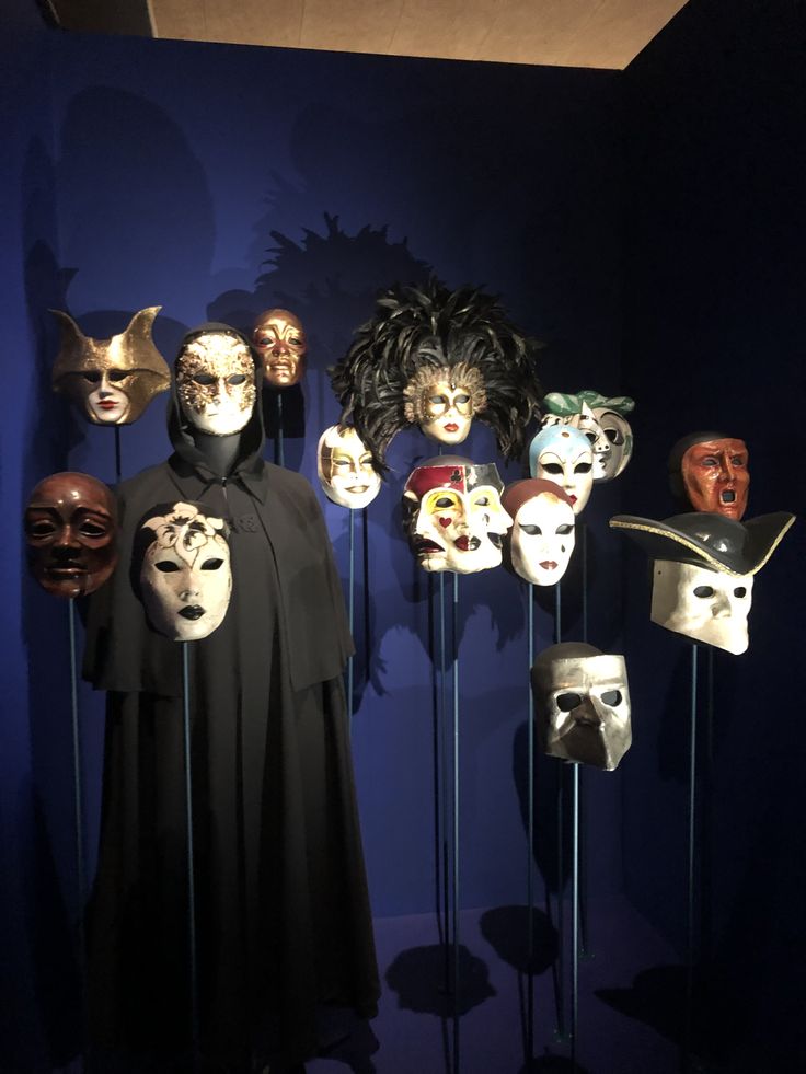 several masks are on sticks in front of a blue wall