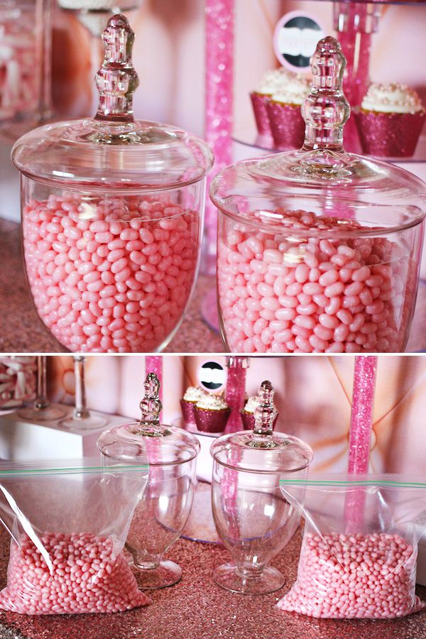 there are pink candies in glass containers on the table