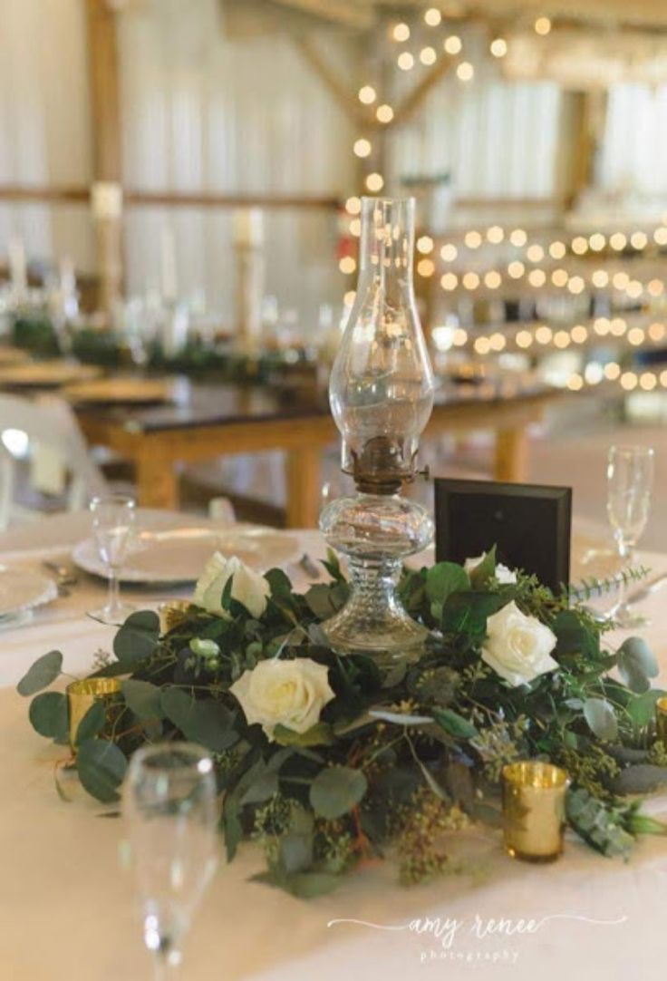 the table is set with white flowers and greenery for an elegant centerpiece or centerpiece