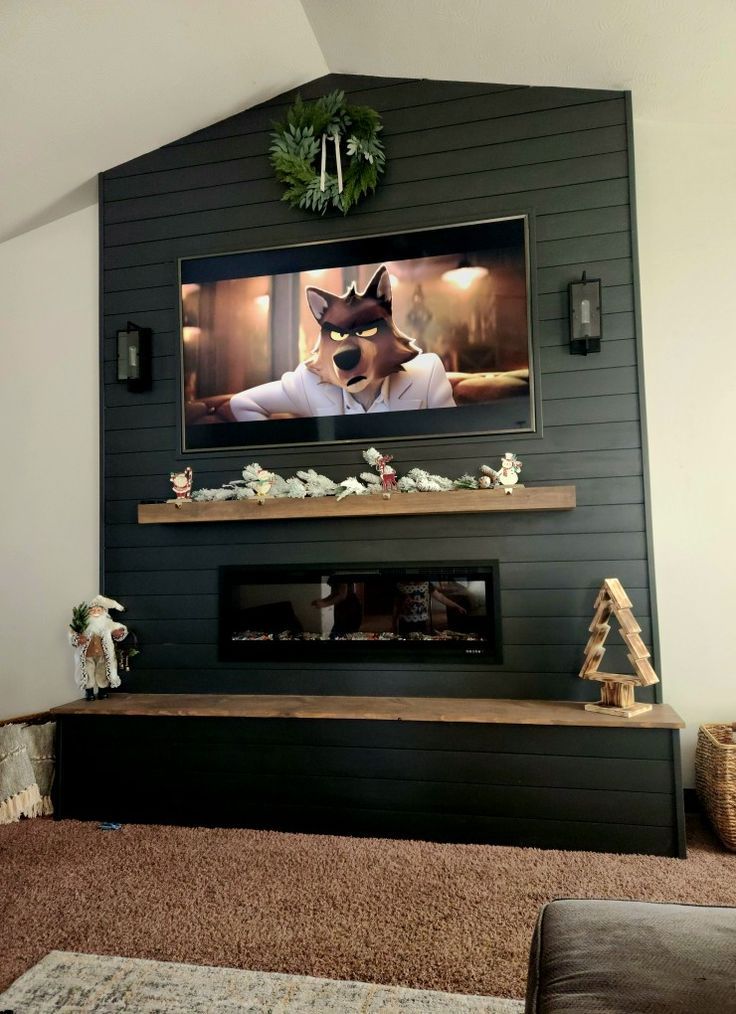 a living room with a large television mounted on the wall above a fireplace and decorated christmas tree