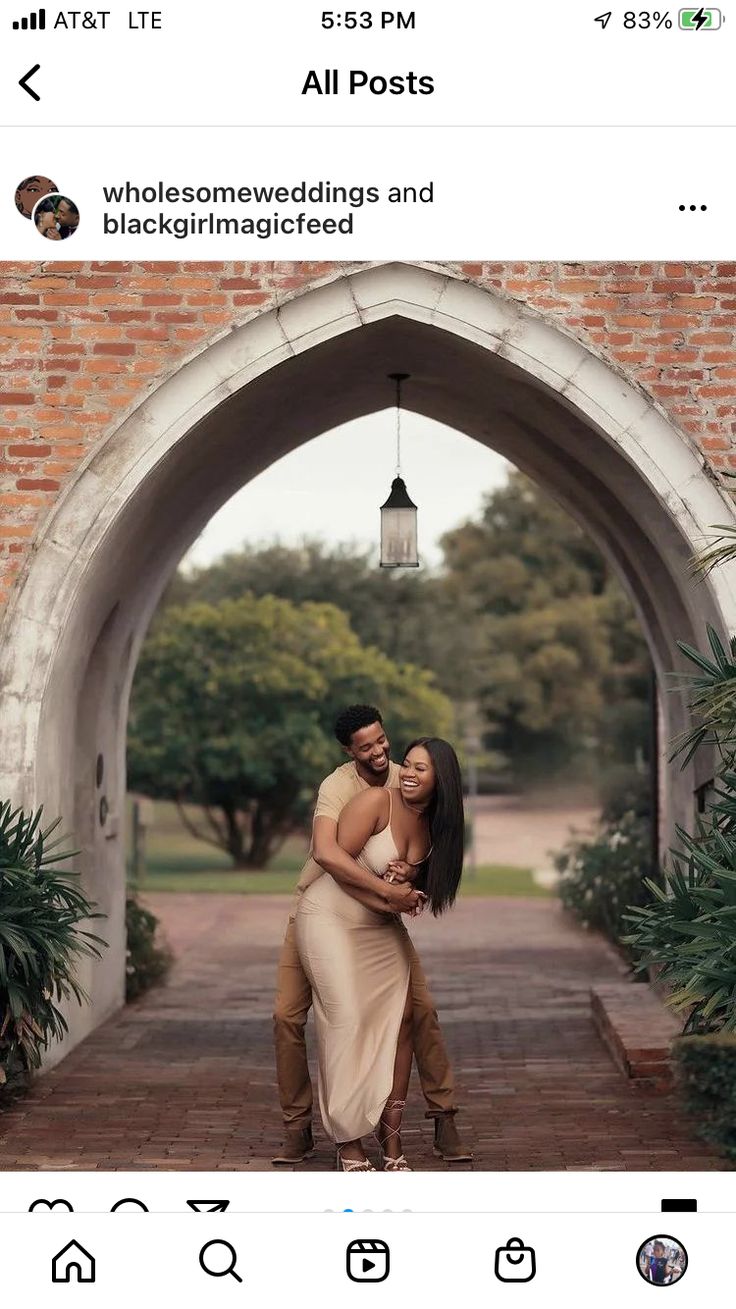 a man and woman hugging each other in front of an archway