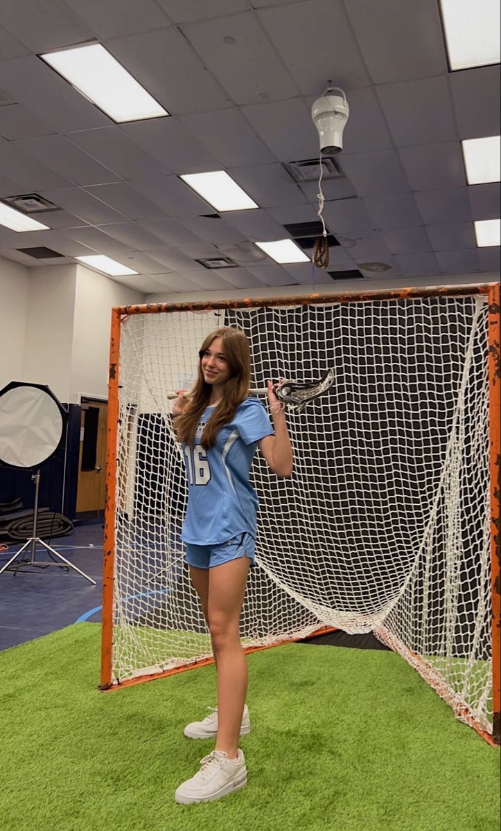 a woman standing in front of a net holding a tennis racquet on top of a green field