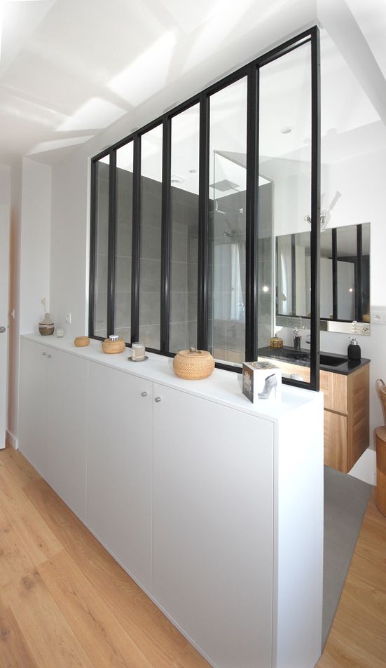 an empty kitchen with white cabinets and black windows on the wall, along with wooden flooring