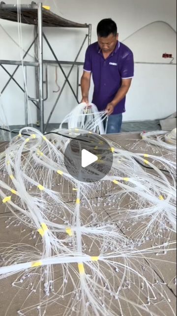 a man in purple shirt standing over a table with white wires on top of it