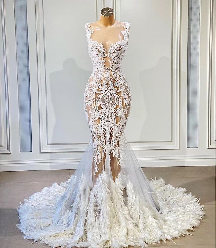 a wedding dress on display in front of a white wall with large windows and doors behind it