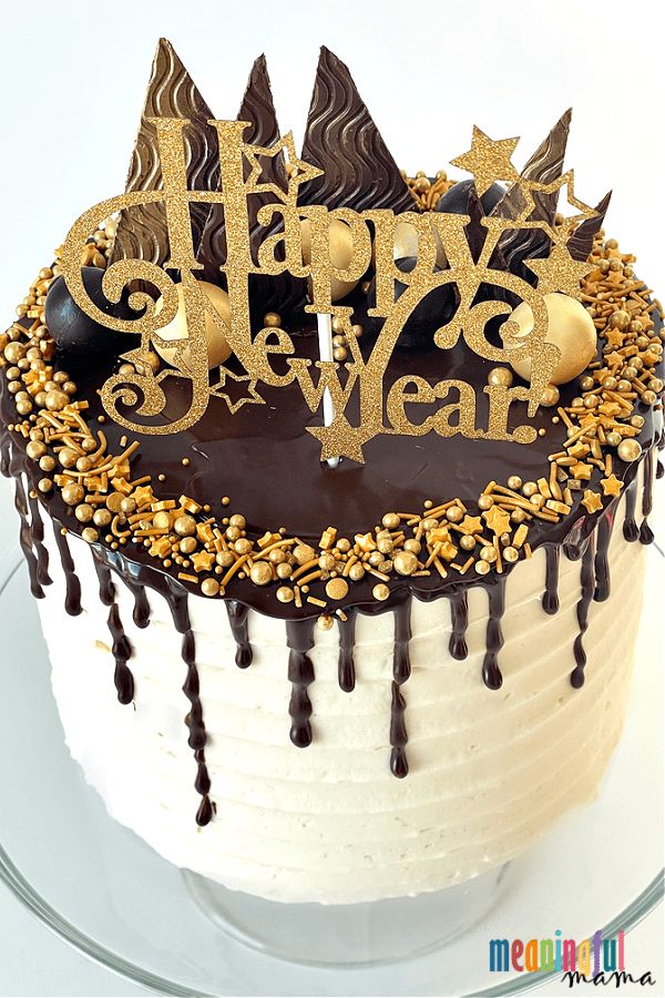 a birthday cake with chocolate icing and gold decorations on top that says happy new year