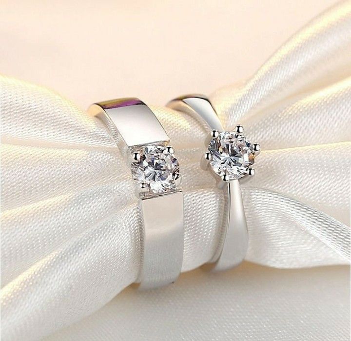 two white gold wedding rings with diamonds on the top and one diamond in the middle