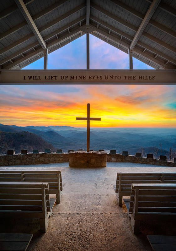 the inside of a church with pews and a cross at sunset in the background