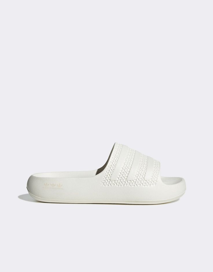 Shoes by adidas Originals Sliding into your cart Slip-on style Branded strap Open toe Molded footbed Chunky sole White Synthetic Slip-on Slippers, Comfortable White Slip-on Slides, White Non-slip Synthetic Slippers, White Slip-on Synthetic Sandals, White Slip-on Flat Slippers, White Synthetic Slip-on Sandals, White Cushioned Slides Slip-on, White Cushioned Slides, Adidas Logo Slides For Beach