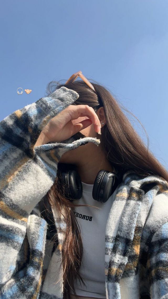 a woman with headphones covering her ears and looking up at the sky in an instagram