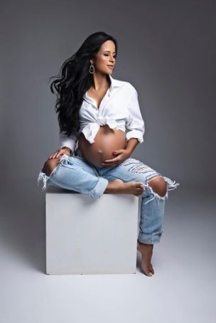 a pregnant woman sitting on top of a white box