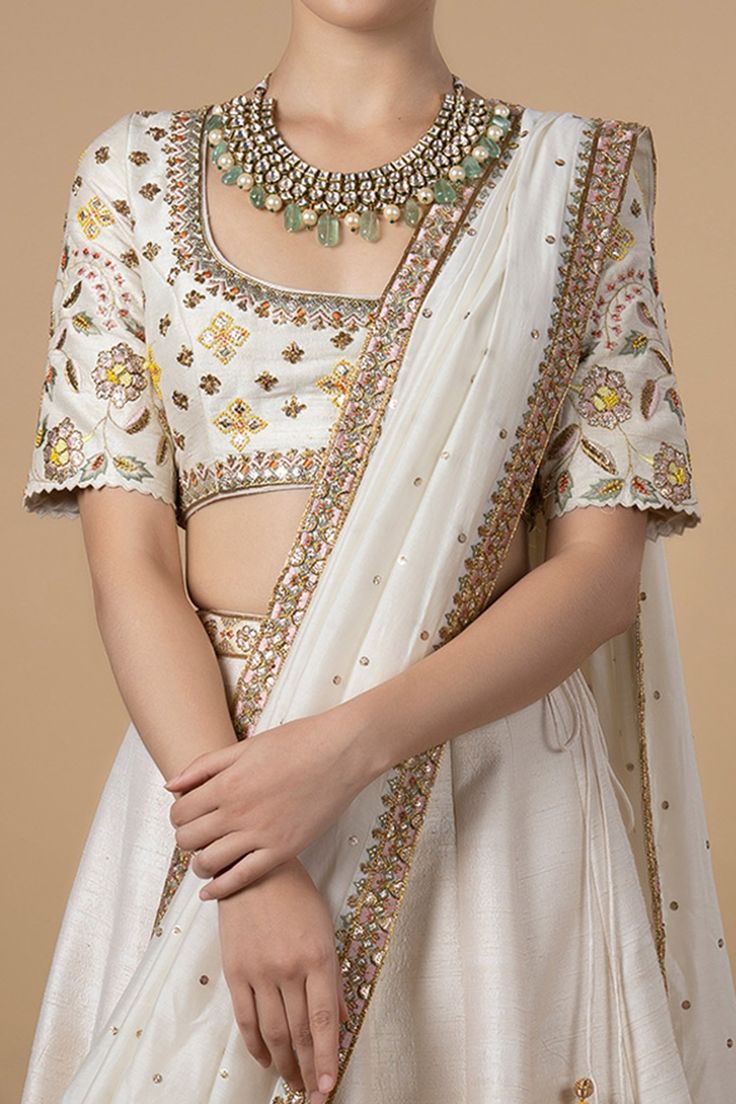 Ivory lehenga with embroidered waistband and floral embroidered hemline. Comes with blouse and dupatta.
Component: 3
Pattern: Embroidery
Type Of Work: Zardozi, beads and Sequin
Neckline: Round
Sleeve Type: Half
Fabric: Dupatta: Cotton Silk, Lining: Shantoon
Color: White
Other Details: 
Cutwork sleeve hems
Dupatta with embellished border
Low back with tie up back
Closure: Blouse: Hook back; Lehenga: Side zip and tie up
Occasion: Wedding - Aza Fashions Ivory Lehenga, Lehenga And Blouse, White Lehenga, Raw Silk Lehenga, Lotus Design, Blue Lotus, Beaded Neckline, Pattern Embroidery, Silk Lehenga