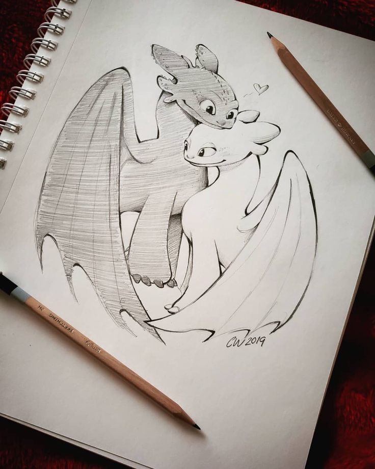 a pencil drawing of a dragon with wings and tail, on top of a notebook