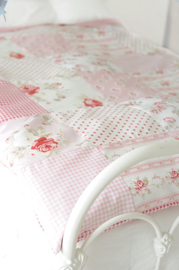 a white bed with pink and white bedspread on it's headboard