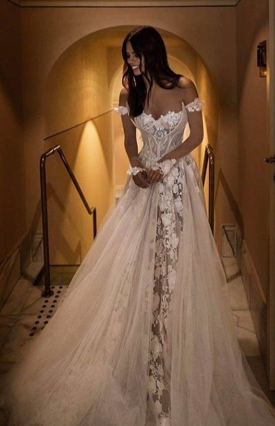 a woman in a wedding dress is standing on the stairs with her hands behind her back