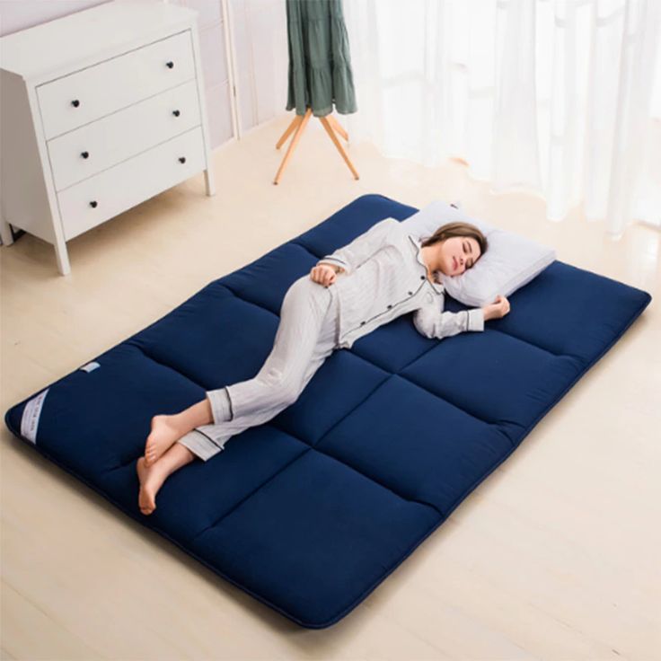 a woman laying on top of a blue mattress