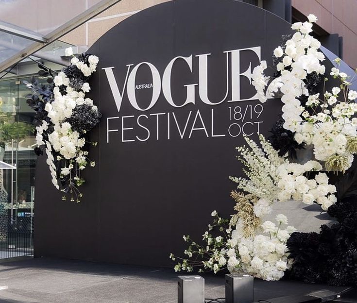 a black and white floral display in front of a large sign that says voque festival