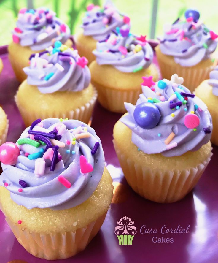 cupcakes with purple frosting and sprinkles are on a plate