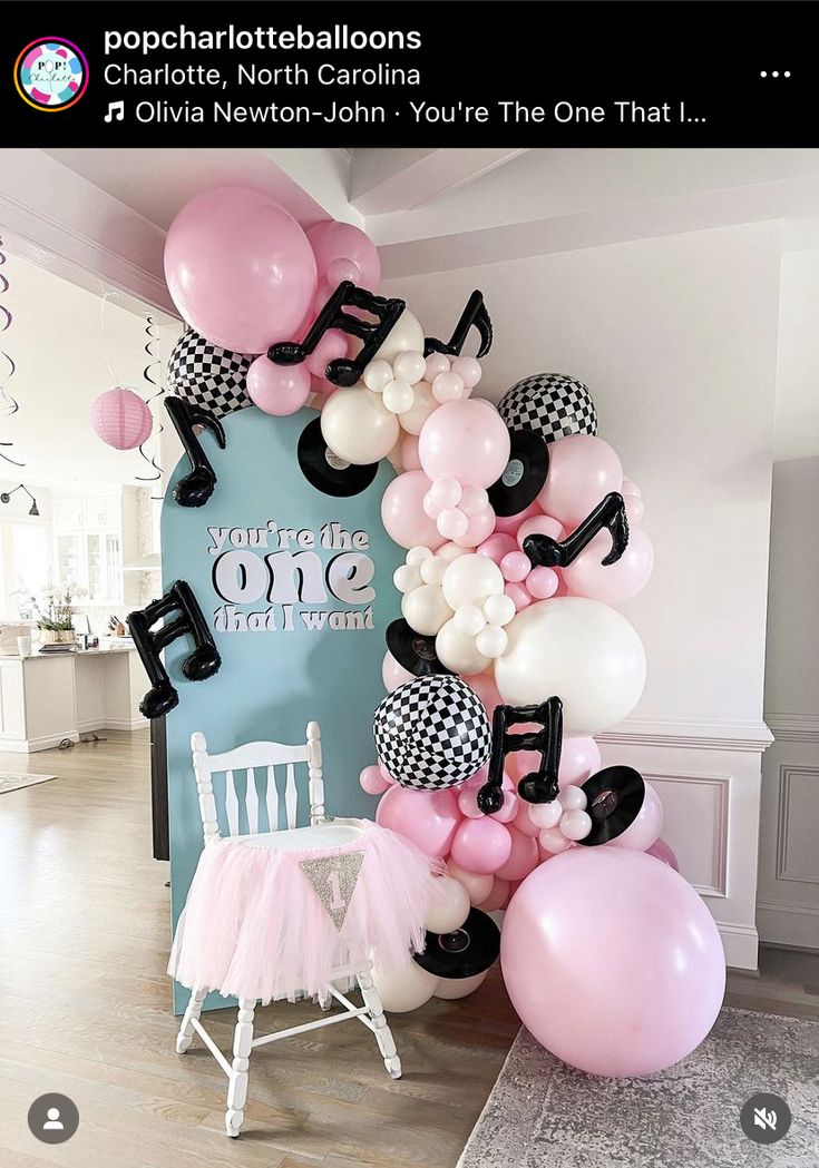 the balloon arch is decorated with musical notes and pink, white, and black balloons