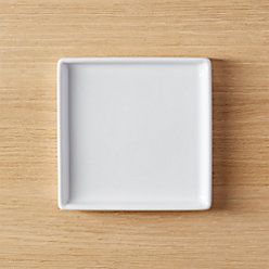 a square white plate sitting on top of a wooden table