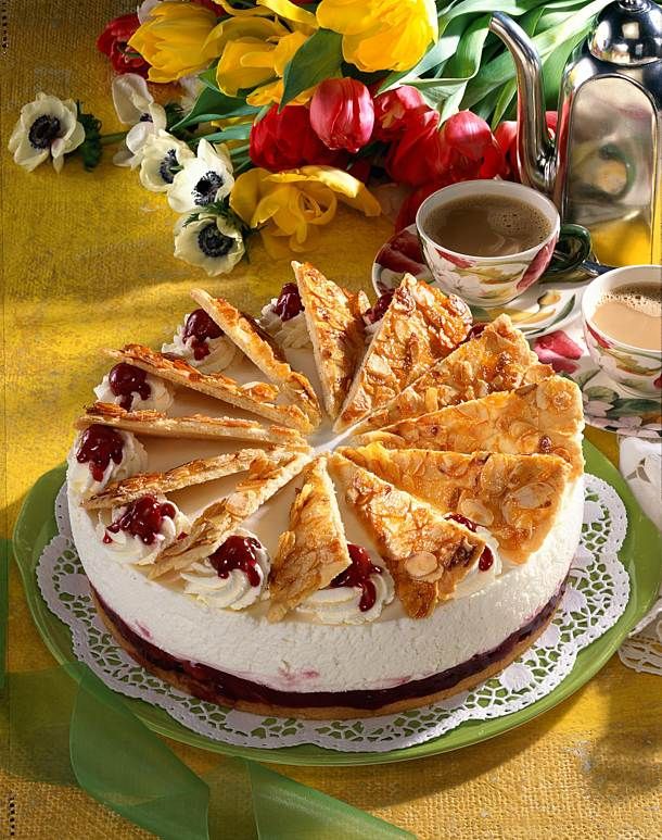 a cake sitting on top of a green plate next to a cup of coffee and flowers