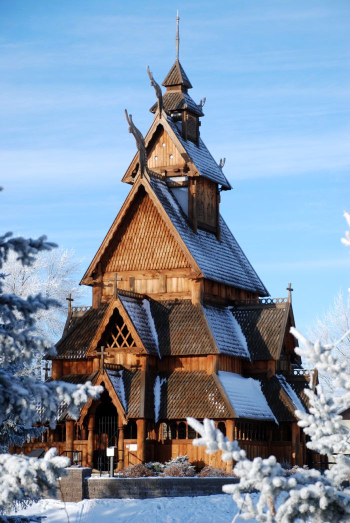 an old wooden church surrounded by snow covered trees