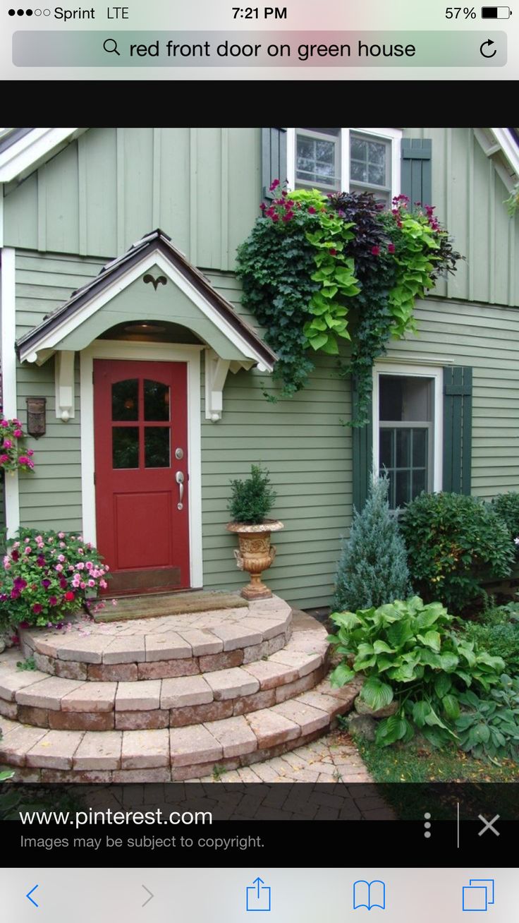 a green house with white shutters on the front door and steps leading up to it