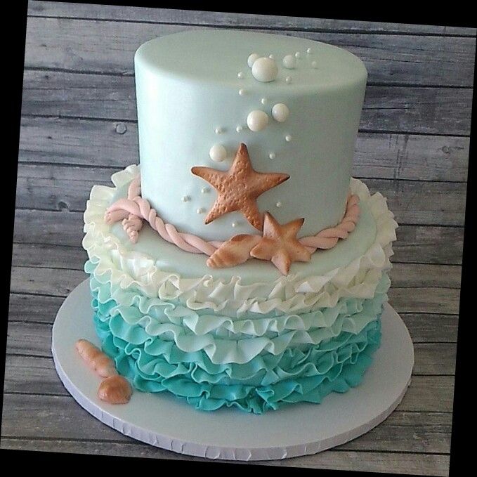 a three tiered cake with starfish and seashells on the top layer