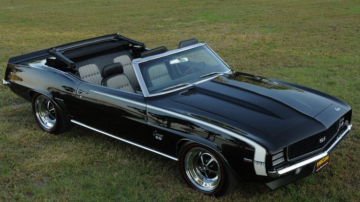 a black car parked on top of a grass covered field