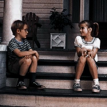 two young children sitting on steps talking to each other