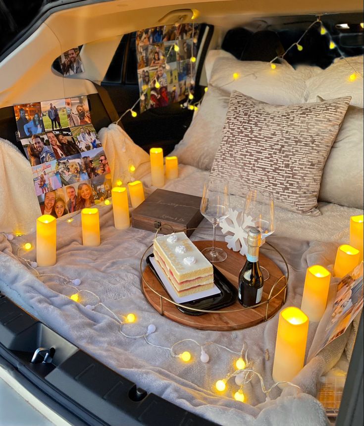 a table with candles and cake on it in the trunk of a car that is parked