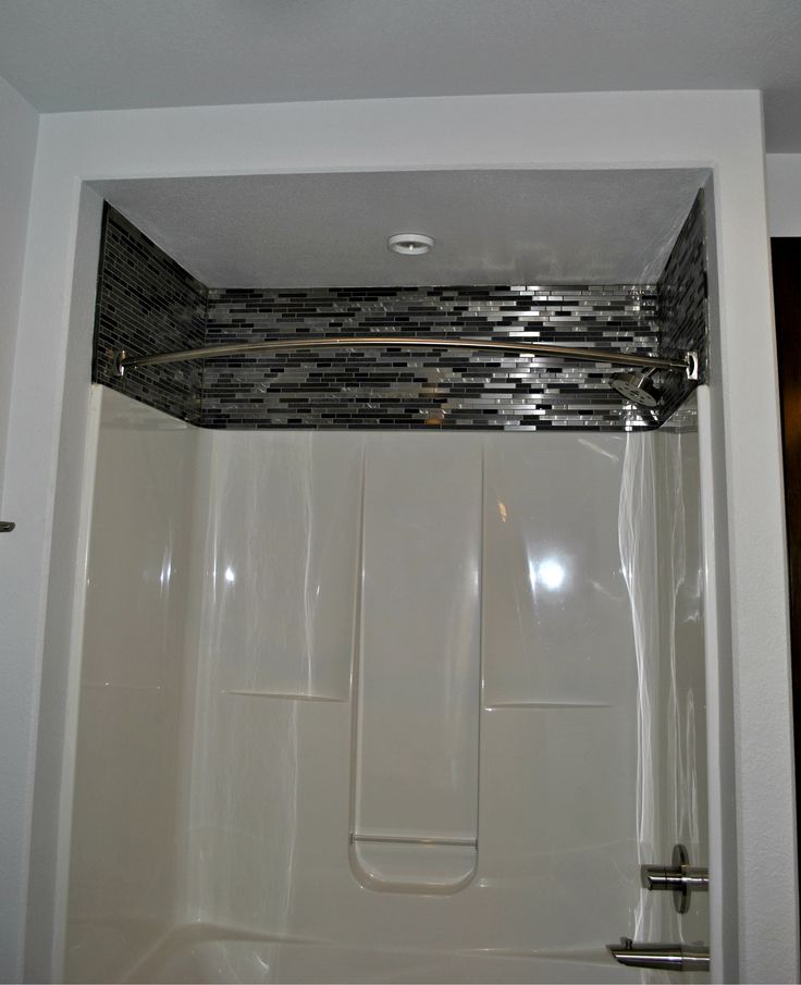 a bath tub sitting inside of a bathroom next to a shower head and hand rail