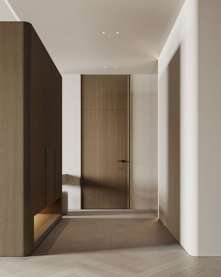 an empty hallway leading to a bedroom with wooden closets and white walls, along with herringbone flooring