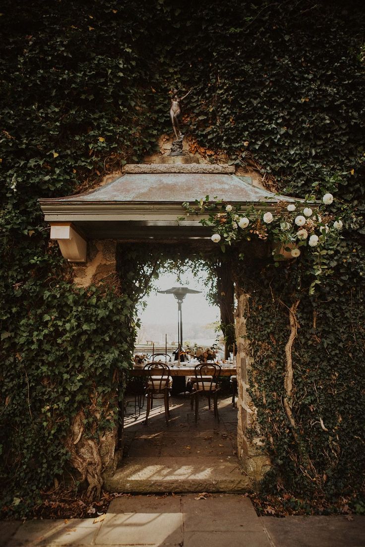 an outdoor dining area covered in vines and flowers