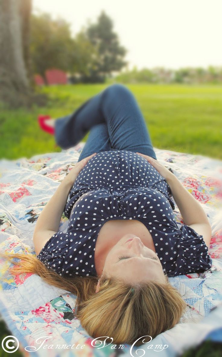 a woman laying on top of a blanket in the grass