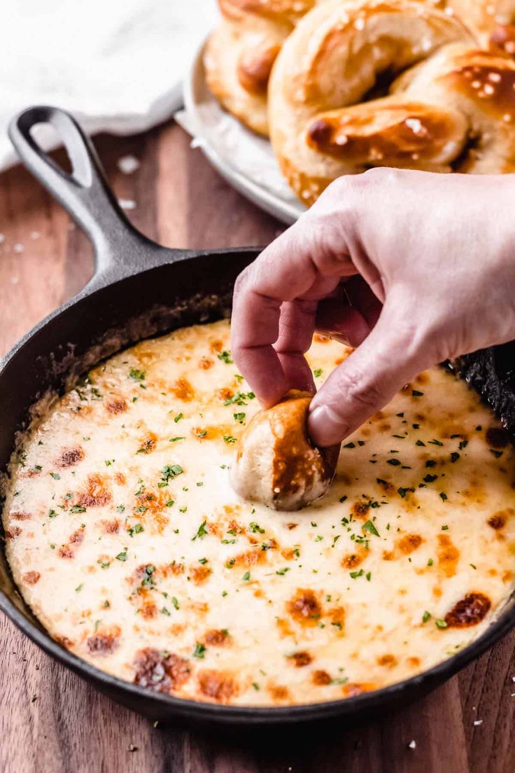 a person dipping cheese into a skillet