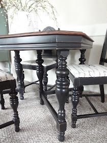 a dining room table with two chairs and a potted plant on the floor next to it