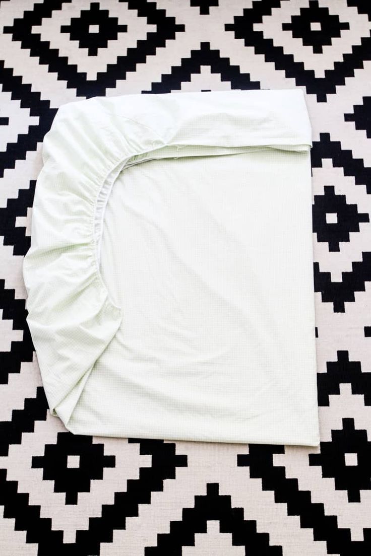 an unmade bed spread on top of a black and white checkered floor