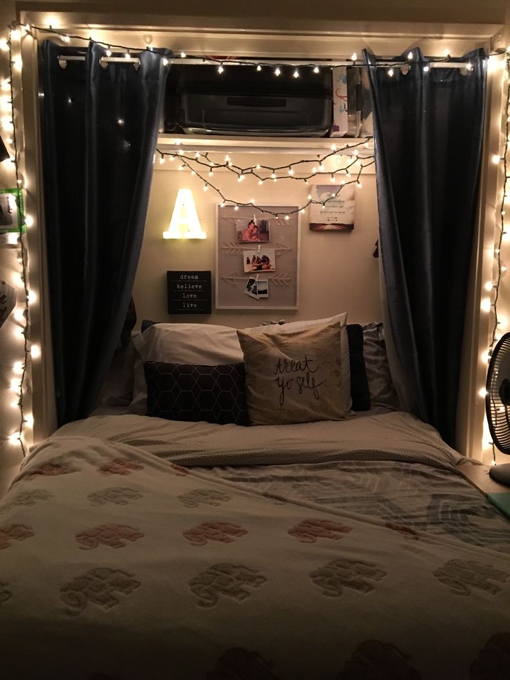 a bed with some lights on the headboard and curtains over it's head