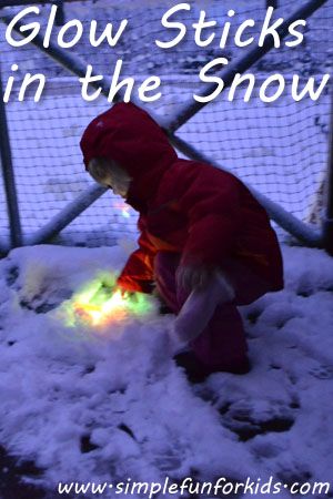 a small child in a red coat playing with some lights on the snow covered ground