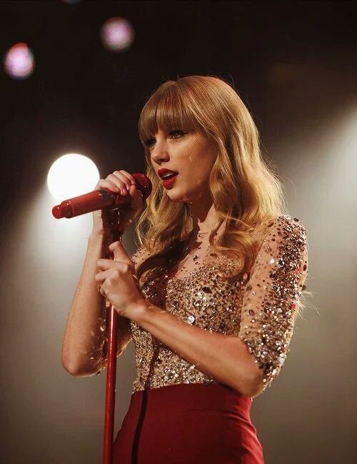 taylor swift performing on stage with microphone in hand