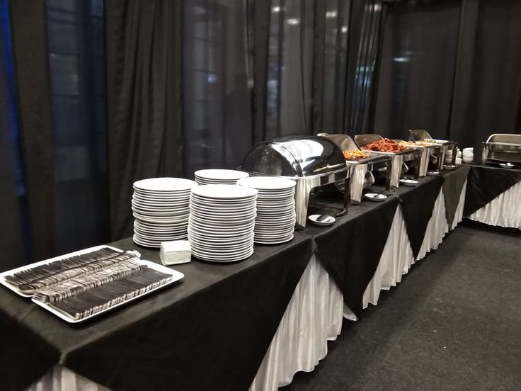 the buffet table is set up with plates and cups on it, ready to be served