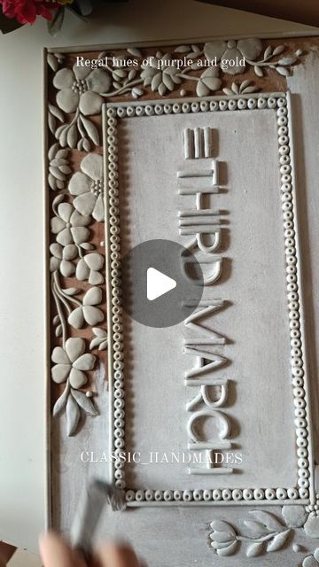 someone is cutting out the word in front of an ornate frame with flowers and leaves