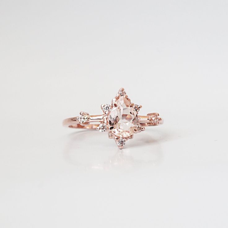 This ring is an elegant beauty for the ages. A peachy morganite set 14K solid gold. Definitely a timeless classic. Available in yellow gold vermeil, rose gold, and silver. Material: - 14K solid gold - Natural Morganite 7x5mm - Round CZs **This item is made to order, please allow 1-2 weeks for your order to be shipped. Shipping: Domestic: Ship via USPS priority mail International: $15 for international standard shipping. $10 to Canada. Online Return Policy: Due to the made to order nature, this r Classic Morganite Jewelry With Prong Setting, Elegant Morganite Rings With Diamond Accents, Rose Gold Rings With Diamond Accents And Morganite, Elegant Morganite Diamond Ring With Gemstone, Classic Morganite Jewelry With Accent Stones, Classic Morganite Jewelry With Accents, Formal Fine Jewelry Blush Rings, Fine Jewelry Morganite Diamond Ring In Rose Gold, Fine Jewelry Rose Gold Morganite Diamond Ring