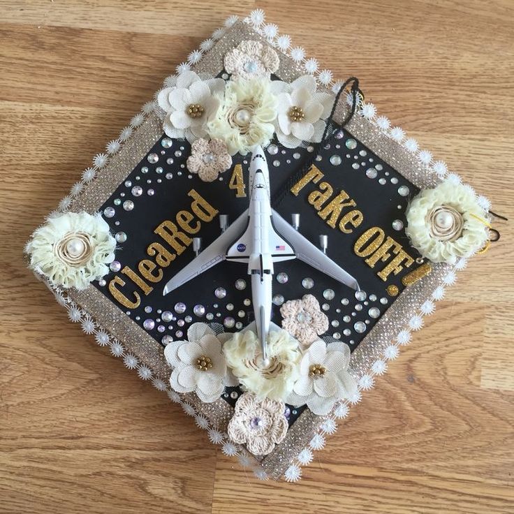 a clock made to look like an airplane with flowers on the front and bottom, sitting on a wooden surface