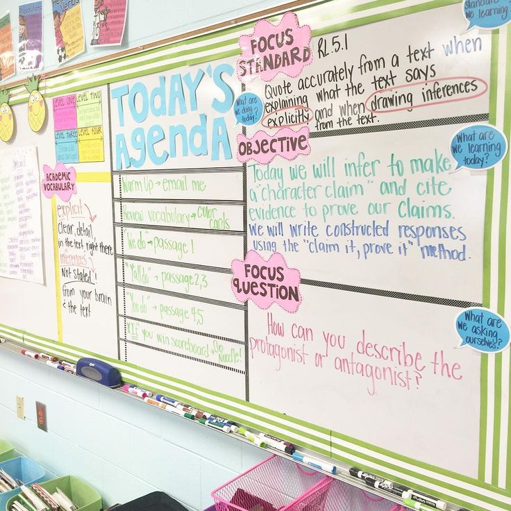 a bulletin board with lots of writing on it and some bins in front of it